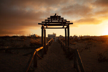 Wooden pergola and boardwalk on beach at sunrise in Cadiz