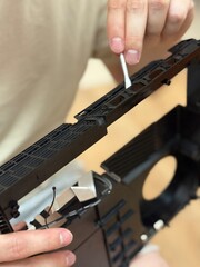 Close-up of a person cleaning an electronic device case with a cotton swab. Hardware maintenance, dust removal and device care at home