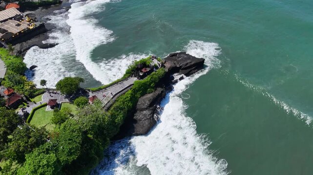 Drone video of an aerial view of Tanah Lot beach with rocks jutting out into the beach