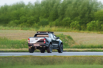Fototapeta premium Versatile pickup crossing green rural environment
