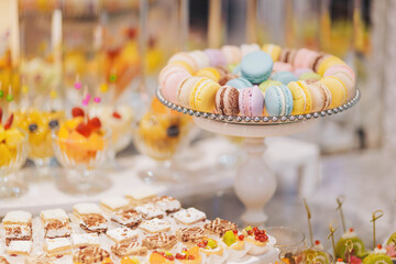 Colorful dessert display featuring macarons, fruit cups, and sweet treats in an elegant setting during a festive gathering
