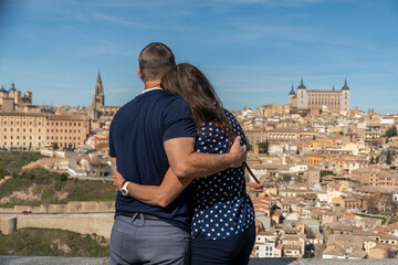 A man and a woman are embracing each other while gazing at a city skyline