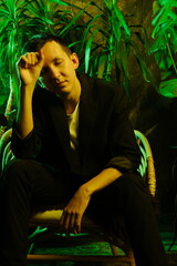 Fashionable man relaxes amid jungleinspired decor and moody lighting