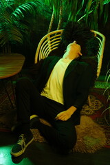 Serene individual seated among lively tropical plants illuminated softly