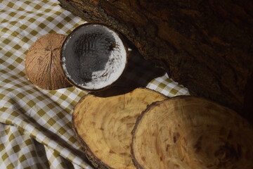 Cenário dramatico ôrganico com coco seco ralado, cepo de árvore, tronco de madeira e tecido quadriculado marrom