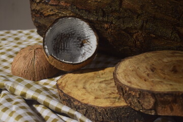 Cenário rústico para exposição de produtos feitos do coco com coco seco ralado, cepos de madeira e tronco de árvore