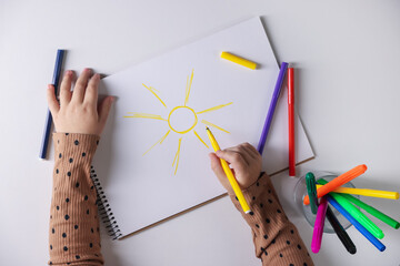 Cute little girl drawing with felt pen at white table, top view