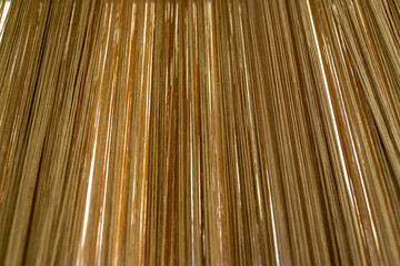 abstract background of thin  mustard color vertical threads or string curtain, creating a textured modern design with soft natural light.