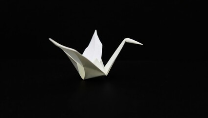 Single white origami crane on a black background