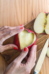 Hands carving a heart into fruit