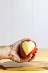 Hand showing an apple with a carved heart