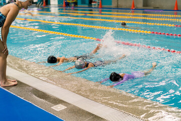 Instructor guiding children learning swimming techniques in pool
