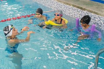 Instructor teaching children swimming lessons in pool