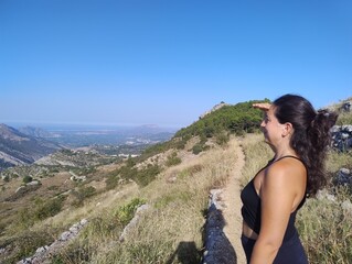 Woman Enjoying Scenic Mountain View on a Sunny Hiking Trail