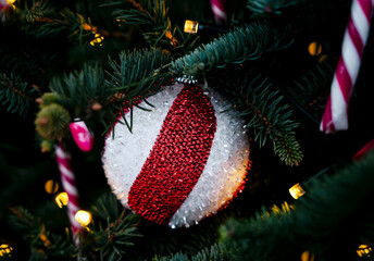 Festive Christmas ornament with a round bauble with a bold red and white striped. The atmosphere feels cozy and magica. Close-up. Selective focus.