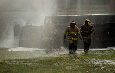 A group of firefighter run through Water mist and heavy smoke holding a rescue axe