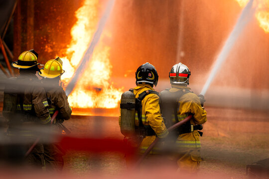 A group of firefighters uses high-pressure hoses to battle a massive blaze