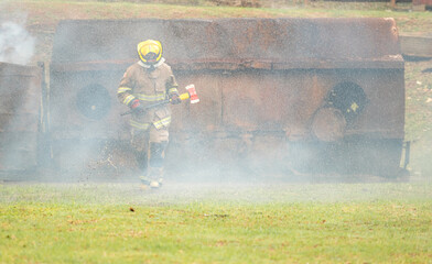 Fototapeta premium A firefighter run through Water mist and heavy smoke holding a rescue axe