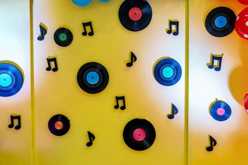 A wall of vinyl records and music notes on a yellow wall