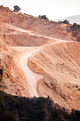 Dusty Winding Road on Red-Toned Quarry Slope