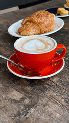 Red cup coffee morning with croissant breakfast on rustic table concept of café, bakery, restaurant