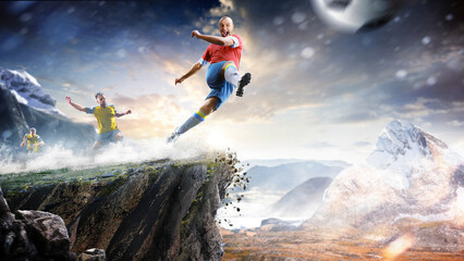 Soccer players in action high in the mountains on the edge of a cliff. Sports concept. Extreme sports moment. Panorama. Cliff. Football players.