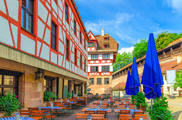 Old half-timbered buildings medieval houses, street restaurants outdoor cafe and city wall on Tiergartnertor Square in old town Nuremberg city center, Middle Franconia region, Bavaria state, Germany