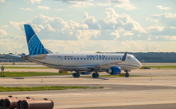 Chicago, Illinois, USA. Nov 18, 2025. Side view of a United Express (operated by Mesa Airlines) Embraer E175 jet with N-number N740YX taxiing on a taxiway under a dramatic cloudy sky.