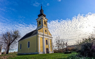 Fototapeta premium Village church on a hill with fence and cloudy sky 