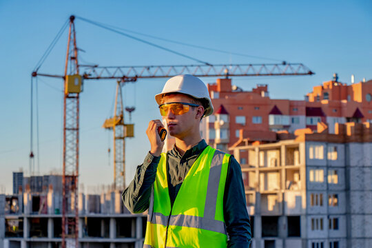 A construction worker talking on a cell phone in front of a construction site