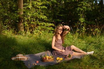 Relaxed woman enjoying sunny meadow with fruits and accessories