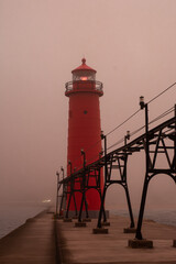 Sunrise on a foggy morning on the Grand Haven south pierhead with the inner light beacon and outer lighthouse.