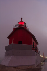 Sunrise on a foggy morning on the Grand Haven south pierhead with the inner light beacon and outer lighthouse.