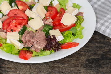 Salad of duck meat with brie cheese and different greens