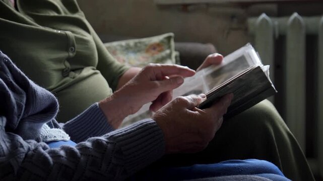 Older adults indulge in tranquil time watching photo album together. Aged persons enjoying calm and companionable looking vintage photo experience. Senior citizens participating in storytelling