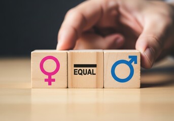 A hand places wooden blocks with gender symbols and the word equal in the center, representing gender equality and balance
