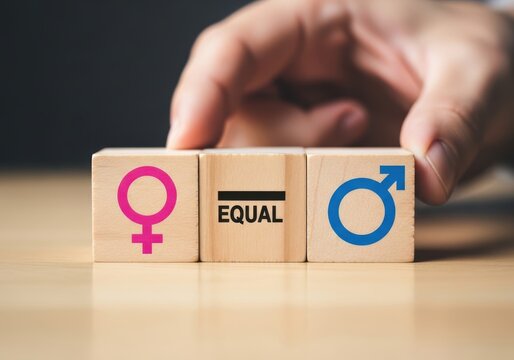 A hand places wooden blocks with gender symbols and the word equal in the center, representing gender equality and balance