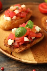 Tasty bruschettas with tomatoes, mozzarella cheese and basil served on wooden table, closeup