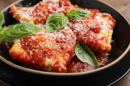 Delicious ravioli with tomato sauce, cheese and basil on table, closeup - Powered by Adobe