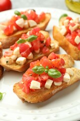 Tasty bruschettas with mozzarella cheese, tomatoes and basil on grey table, closeup