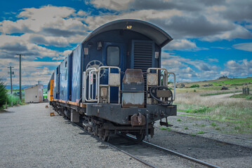 Fototapeta premium Vintage blue train car on tracks with a cloudy sky in the background