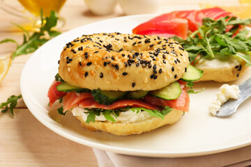 Delicious bagels with salmon served on wooden table, closeup