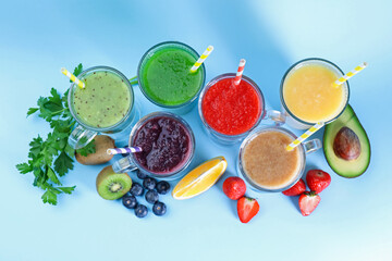 Different tasty smoothies in glasses and ingredients on light blue background, flat lay