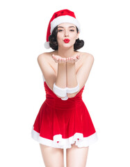 A beautiful woman in a Santa Claus costume blowing a kiss. An attractive holiday pin-up model isolated on a transparent background for Christmas greetings, ads, cards, banners, party flyer, event. PNG