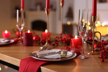 Christmas place setting with festive decor on wooden table in room, closeup