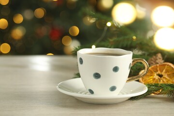 Aromatic coffee and Christmas decor on white wooden table against blurred lights, closeup. Space for text