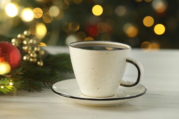 Obraz premium Aromatic coffee and Christmas decor on white wooden table against blurred lights, closeup