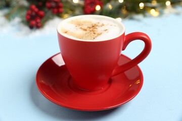 Aromatic coffee in cup and Christmas decor on light blue background, closeup