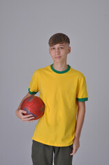 garoto adolescente usando cores do brasil verde e amarelo segurando bola de futebol 