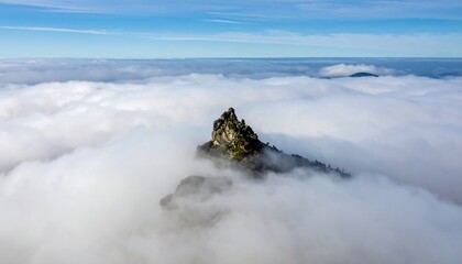 Lone mountain peak rising above foggy clouds